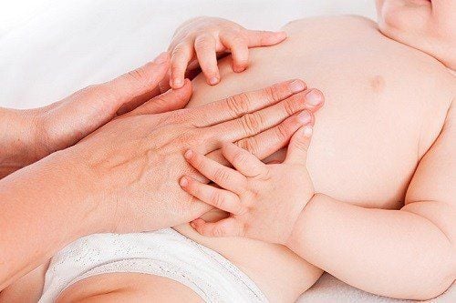 Mẹ đang massage bụng cho trẻ bị táo bón để kích thích nhu động ruột